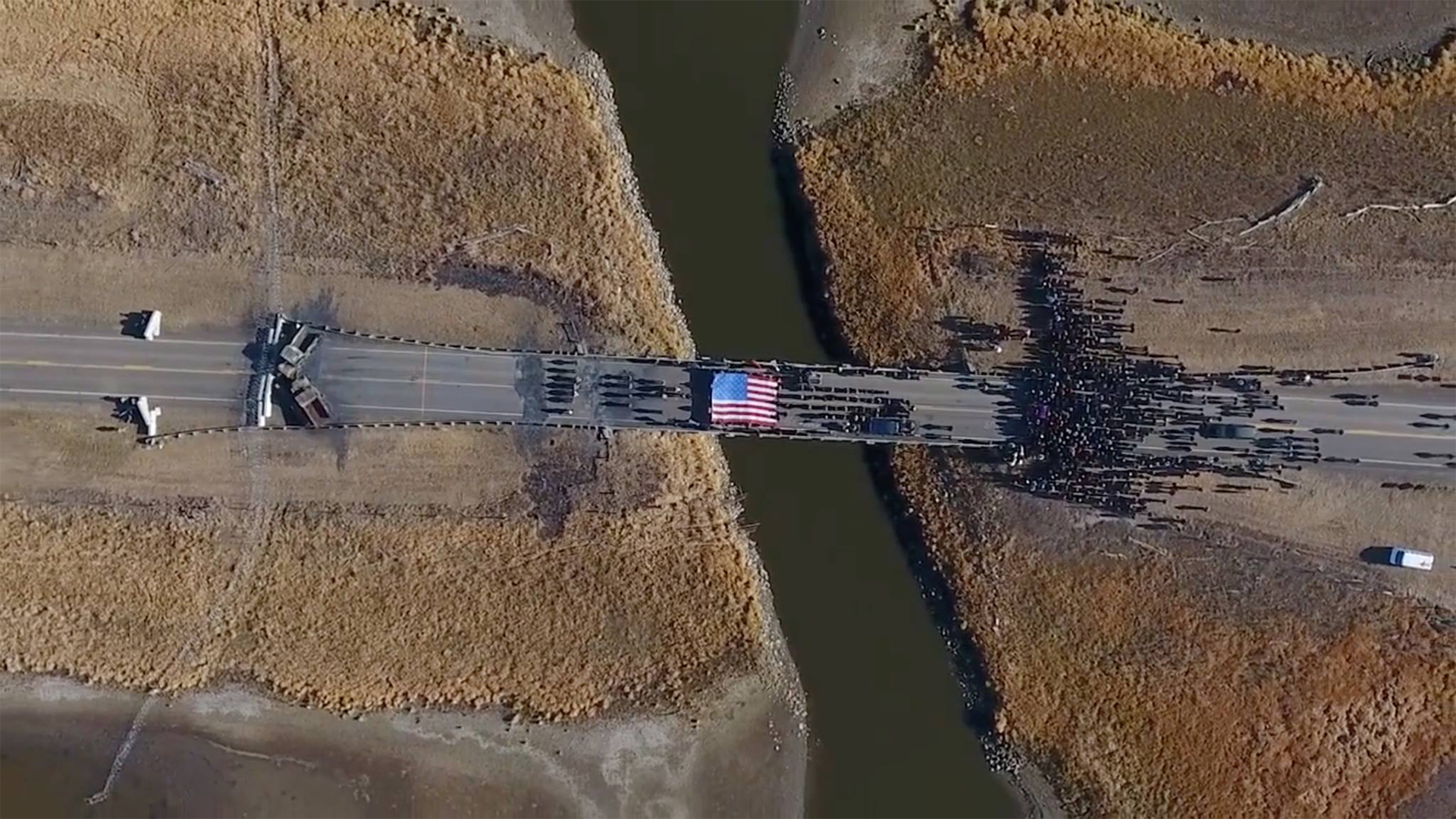 The Backwater Bridge on Highway 1806 over Cantapeda Creek. Water Protectors during a peaceful prayer ceremony in front of the police brigade. Image from the film AWAKE: A DREAM FROM STANDING ROCK captured by Myron Dewey
