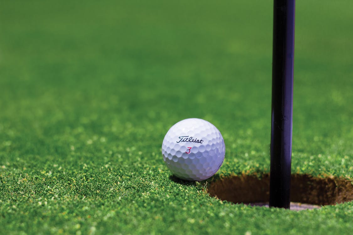 A golf ball next to the pin. Photo by: Tyler Hendy / Pexels.com