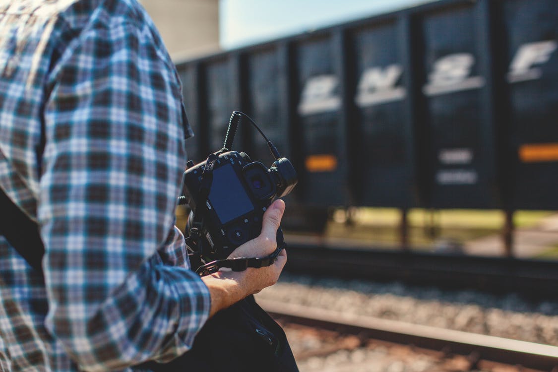 Photographer looking to capture a scene next to a train. Photo by: Pexels.com