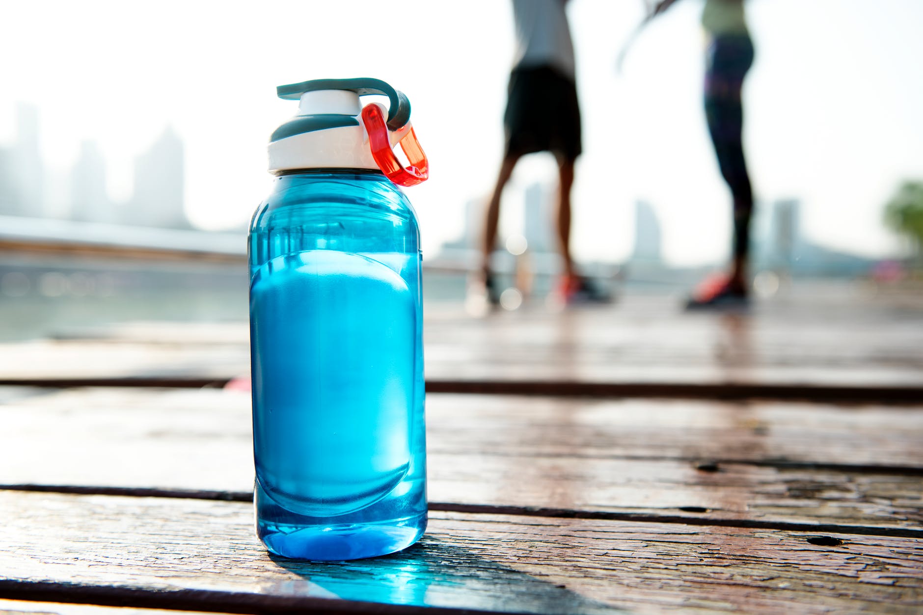 A water bottle with two runners in the background. Photo by: Pexels.com