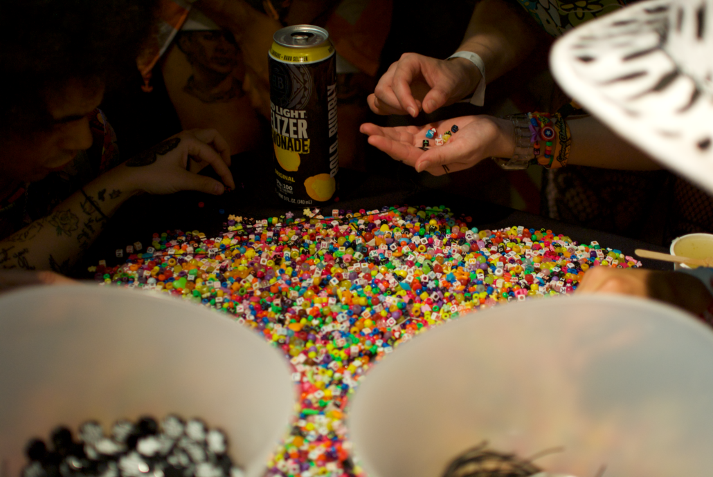 Goldrush attendees sift through plastic beads to make kandi bracelets, multicolored bracelets often made and exchanged at raves and electronic music festivals. Photo by Marissa Novel.